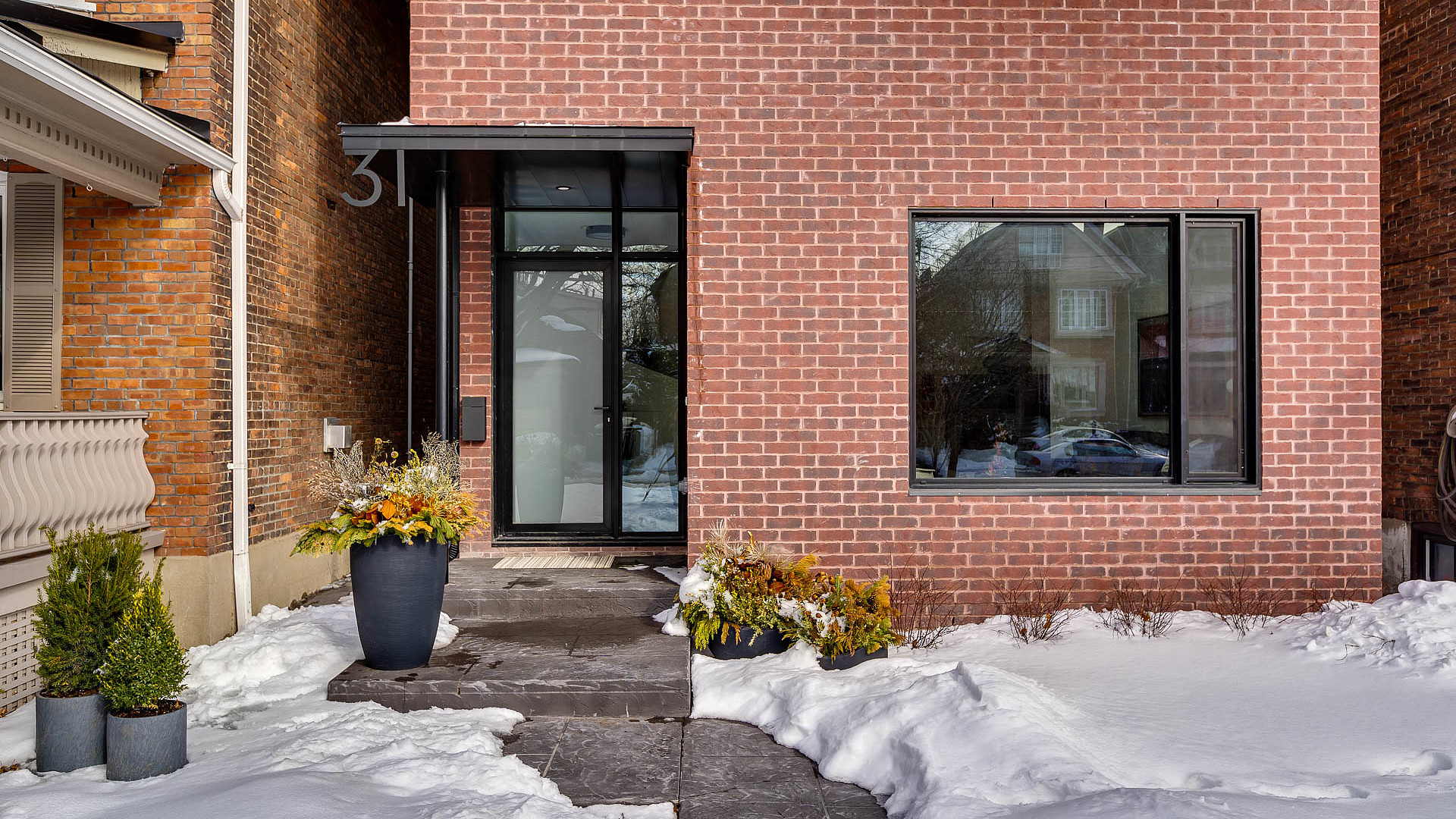 Modern brick custom home entrance with glass door and planters in Toronto