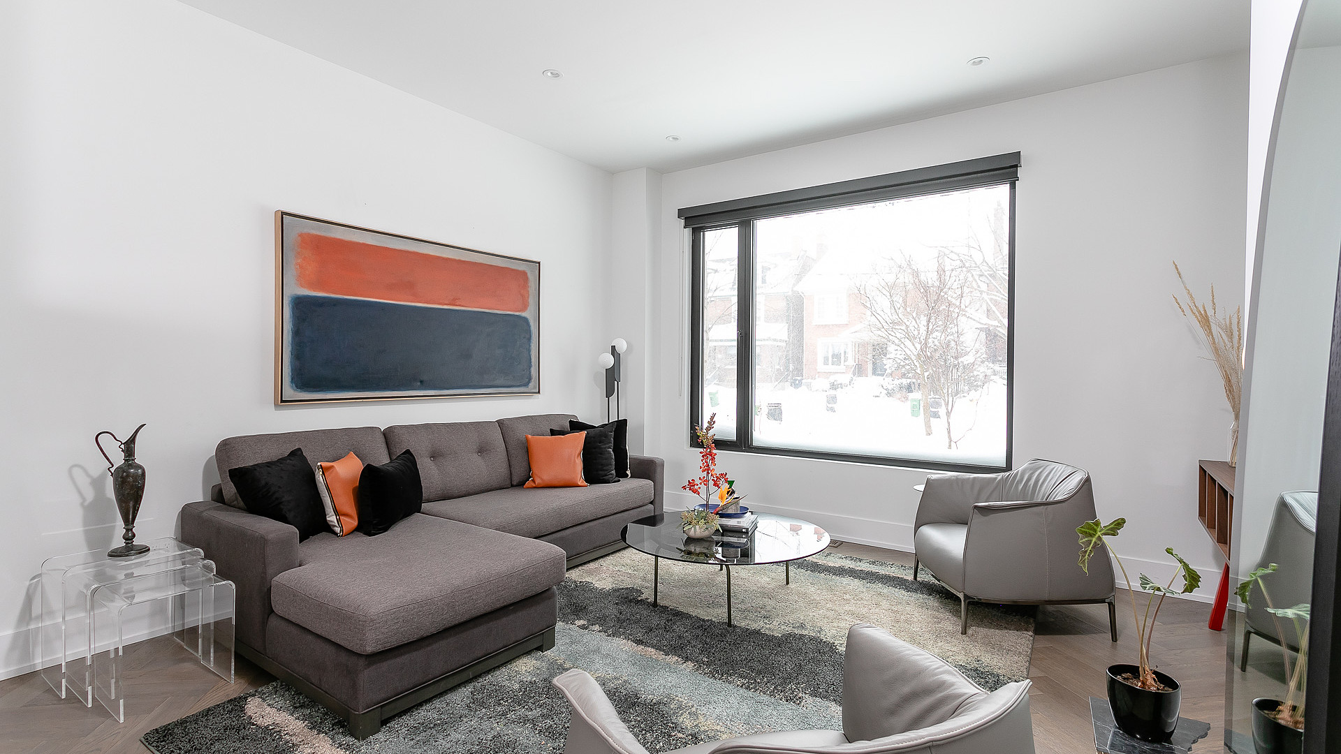Modern living room with herringbone floors and large window in Toronto custom build