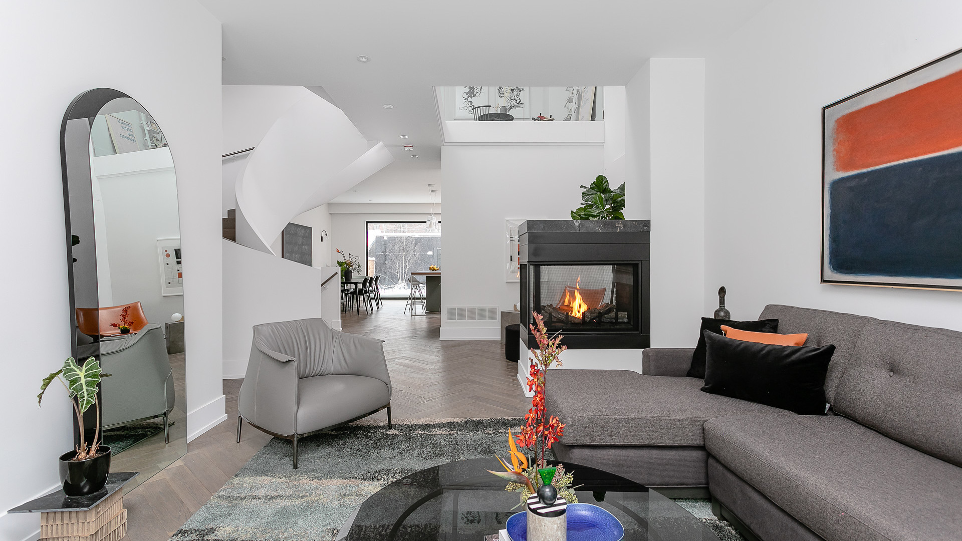 Modern living room with spiral staircase and three-sided fireplace