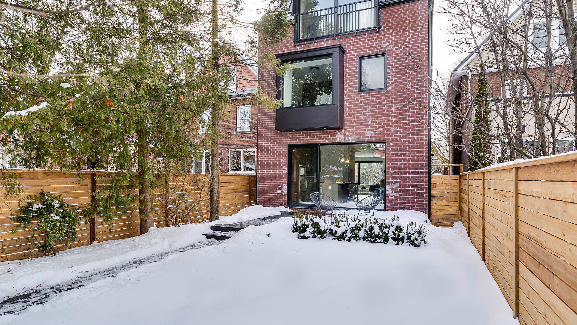 Rear view of custom brick home with cedar fence and patio doors