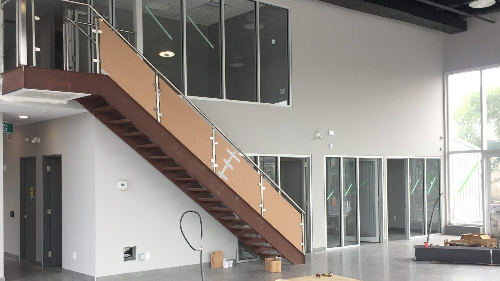 Finished dealership lobby with wooden staircase, glass railings, and mezzanine