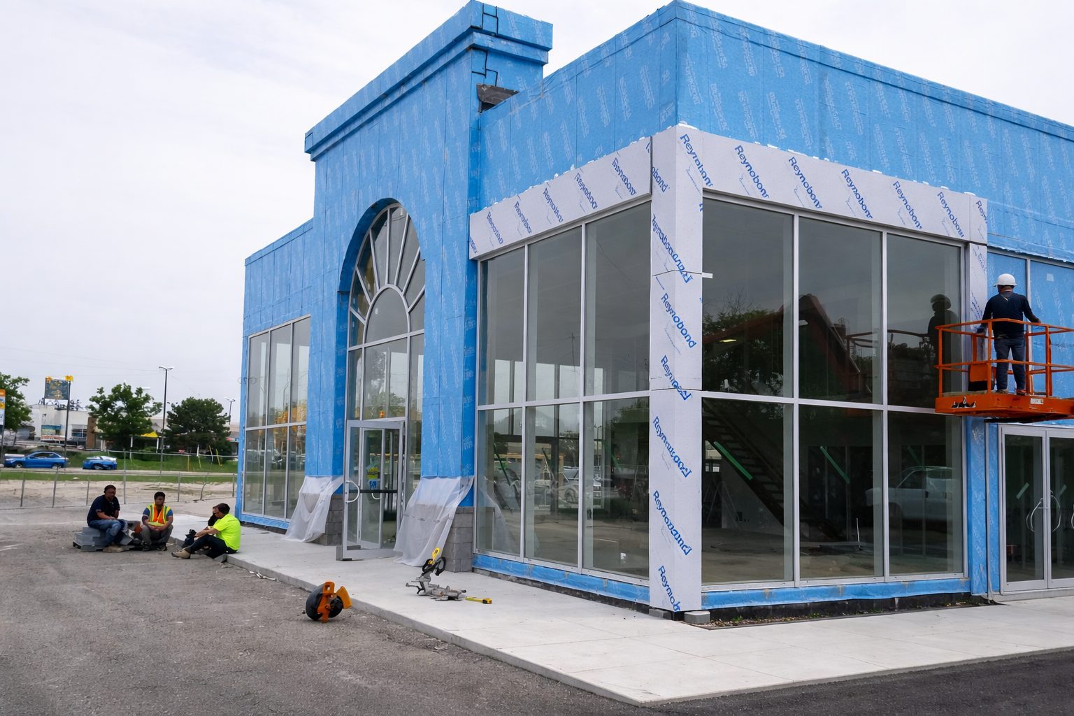 Crew on site installing metal composite panels over Reynobond wrap