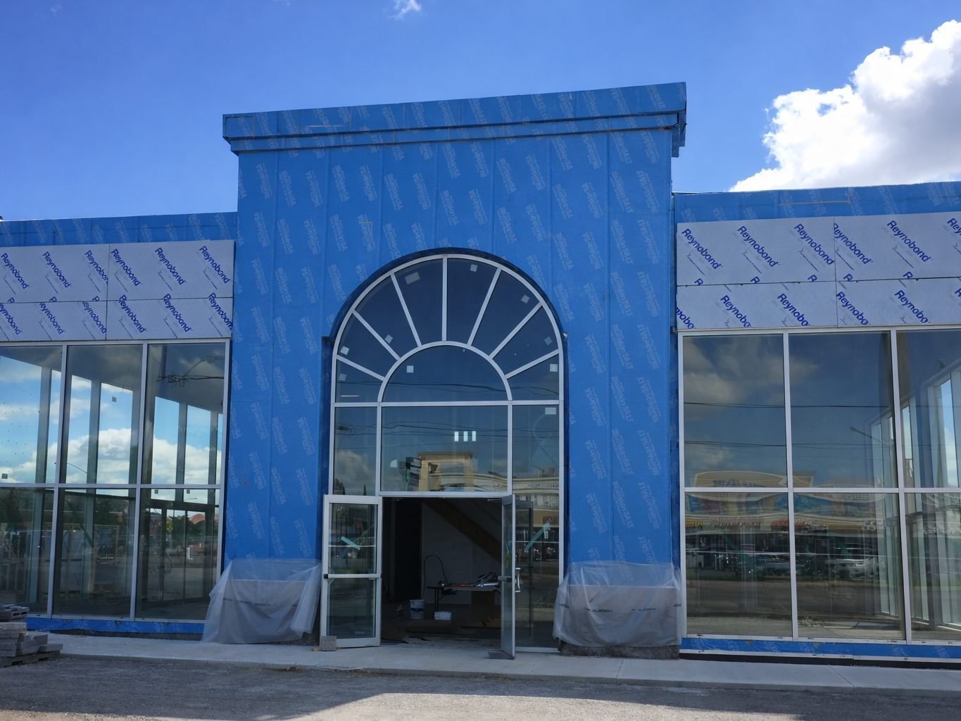 Full Reynobond wrap covering dealership front with arched entrance and glass storefront
