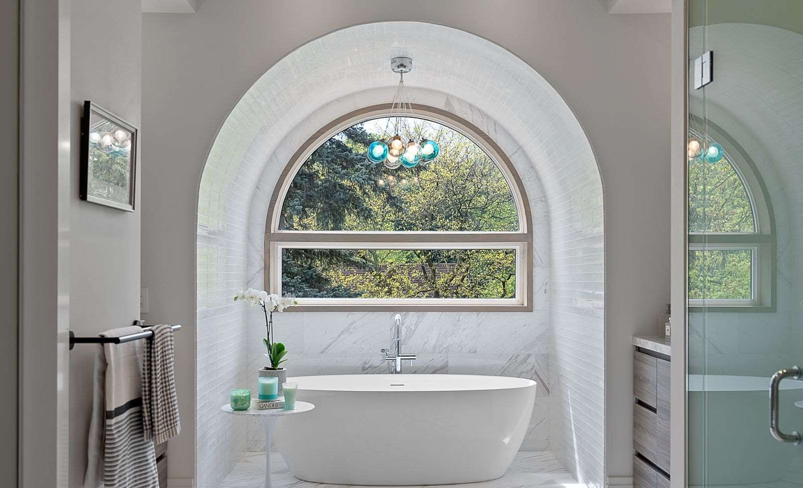Marble arched alcove with freestanding tub and chandelier
