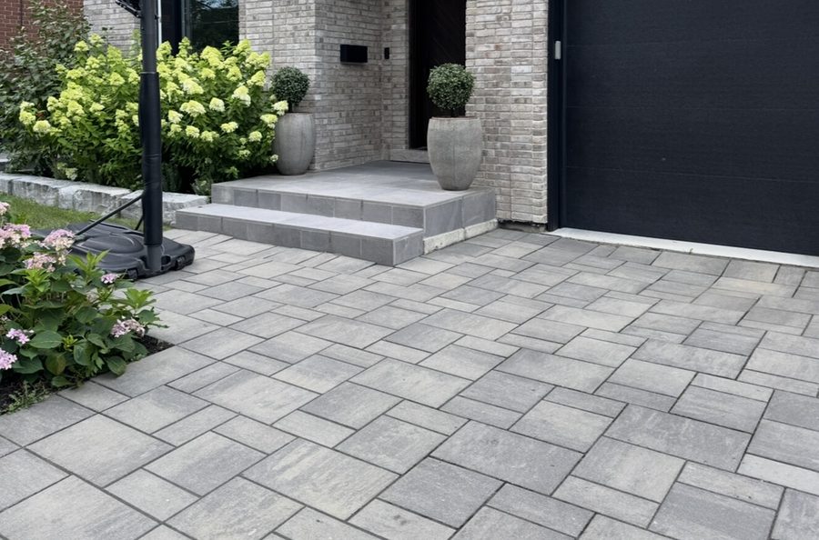 Interlocking paver driveway and stone entrance with landscaping