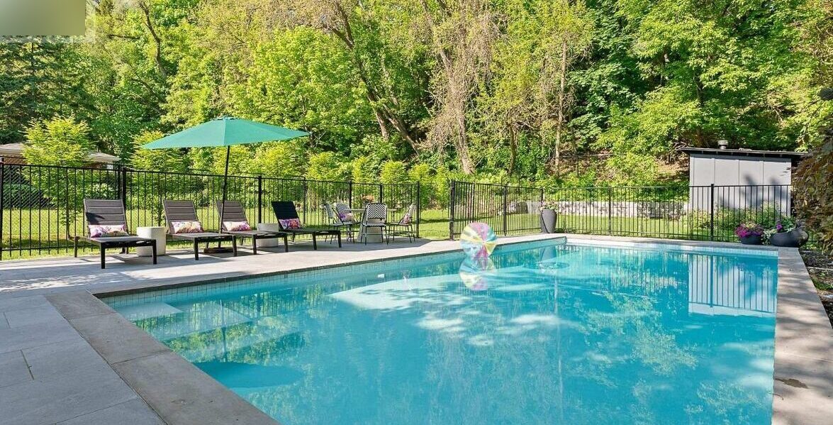 Backyard pool with loungers and mature landscaping